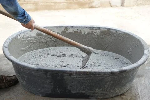 Close up worker using a hoe to mix cement powder, sand, stones in basin for mix Stock Photos