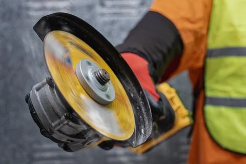 Close-up of a worker using a yellow angle grinder with spinning disc. Build.. Stock Photos