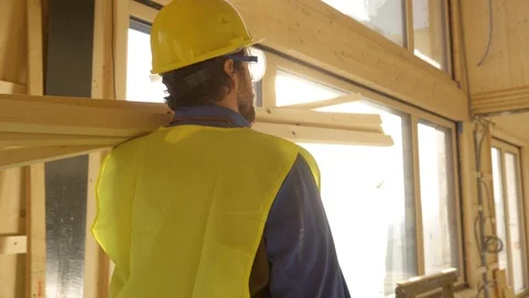 CLOSE UP: Worker walks across a house under construction while carrying beams Stock Footage 124933304