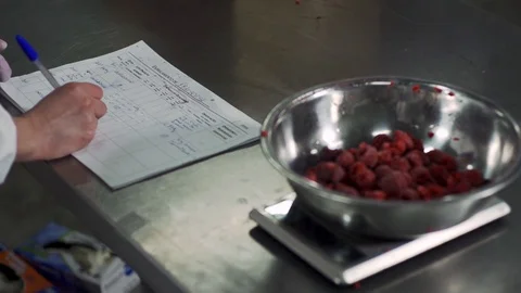 Close up of worker writing down on paper with berries in bowl in slow motion Stock Footage 128963692