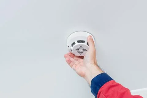 Close up worker's hand installing fire alarm on the ceiling Stock Photos
