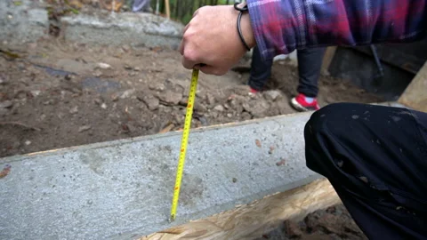 Close up of a worker's hand measuring distance from concrete foundation Stock Footage 158975789