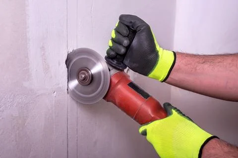 Close-up of worker's hands cutting a wall with an angle grinder Foto stock