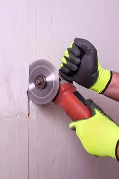 Close-up of worker's hands cutting a wall with an angle grinder Foto stock