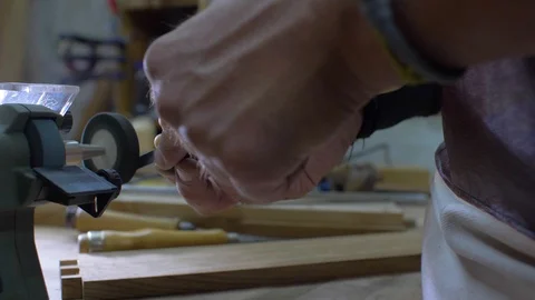 Close-up of a workers hands grinding a chisel on a grinding stone in a workshop Stock Footage 116711433