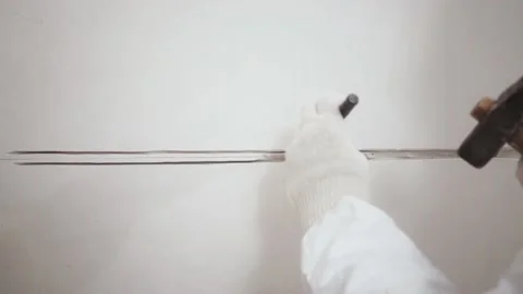 Close-up of worker's hands making a hole in the wall with a chisel and hammer Stockbeeldmateriaal 153773316