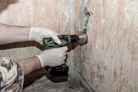 Close-up. worker's hands, protected by gloves, are drilling a concrete wall w Stock Photos