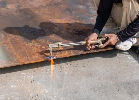 Close-up of a worker's hands using a gas cutting torch to slice through a h.. 스톡 사진