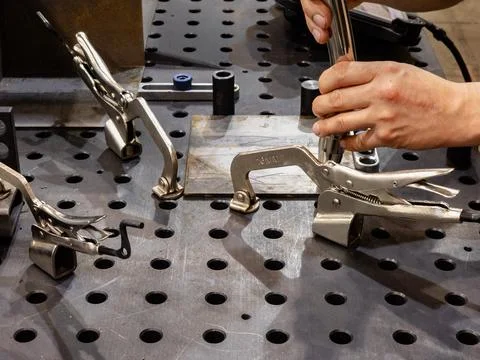 Close-up of a worker's hands using industrial locking clamps and specialized Stock Photos