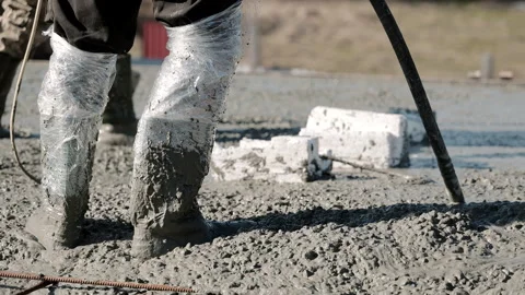 Close-up of workers in rubber boots standing in wet concrete during slab pouring Stock Footage 306403765
