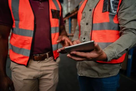Close up of workers tapping on digital tablet choosing delivery plans standing Stock Photos