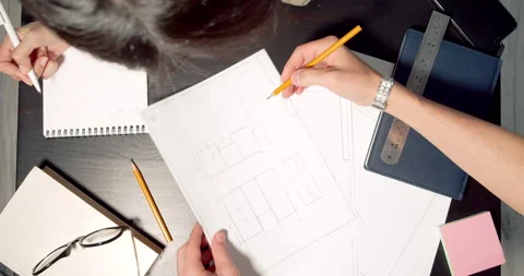 Close up of workplace of two engineers man and woman discussing blueprints and Stock Footage 151005209