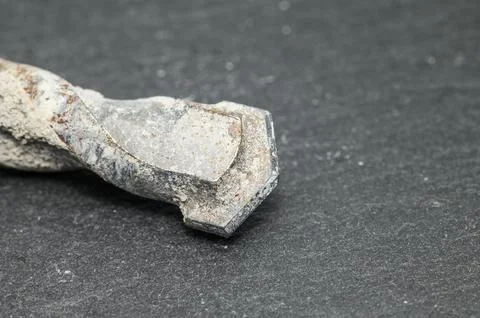 Close-up of a worn and weathered drill bit covered in concrete dust Photos