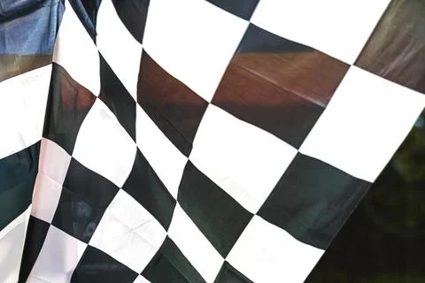Close-up of a worn checkered flag black and white squares, blurred background Stock Photos