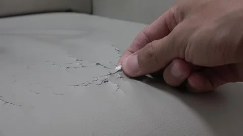 A close-up of worn, cracked leather on an old sofa. Hand picking worn surface. Video stock 329830765