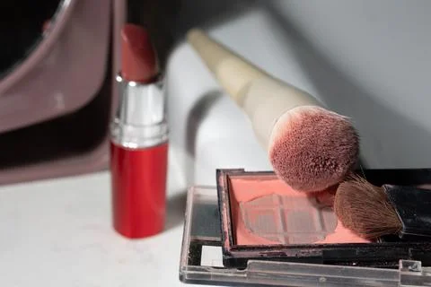 Close-up of worn makeup on a vanity: lipstick worn, blush pan exposed, powder Stock Photos