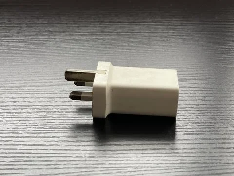 Close-Up Of Worn UK Three-Pin Charger Plug On Dark Surface Stock-Fotos