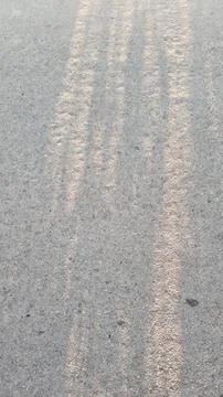 Close up of worn white road marking lines on grey asphalt pavement texture Stock Photos