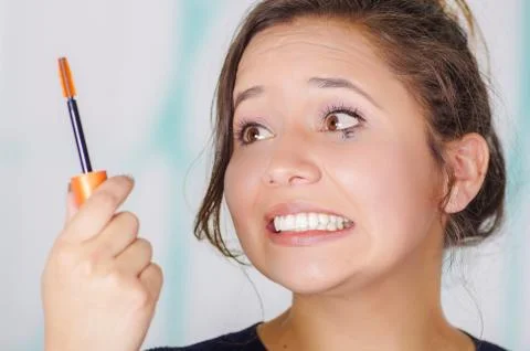 Close up of worried young woman doing a mess using a eye mascara in her eye, in Stock Photos