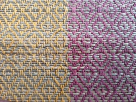 Close-up of a woven textile with a diamond pattern in yellow and pink Stock Photos