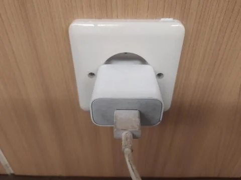 Close up of the wrapped cable on the mobile phone charger plugged into an outlet Stock Photos