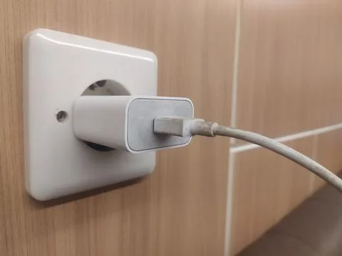 Close up of the wrapped cable on the mobile phone charger plugged into an outlet Stock Photos