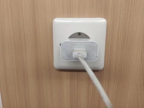Close up of the wrapped cable on the mobile phone charger plugged into an outlet Stock Photos