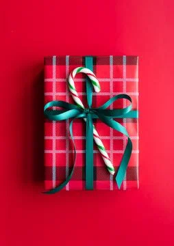 Close up of wrapped Christmas gift with candy cane on red background. 写真素材