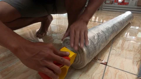 Close Up Wrapping Clean Carpet After Laundry Using Long Plastic And Masking Tape Stock Footage 157394326