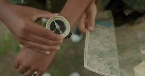 Close up of wrist compass and map in hands outdoor navigation scene Stock Footage 333769705