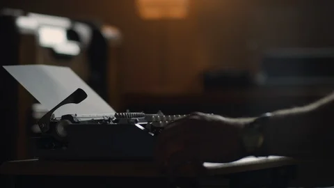 Close up of writer sitting at a vintage typewriter playing with his pen and jour Stock Footage 97872154