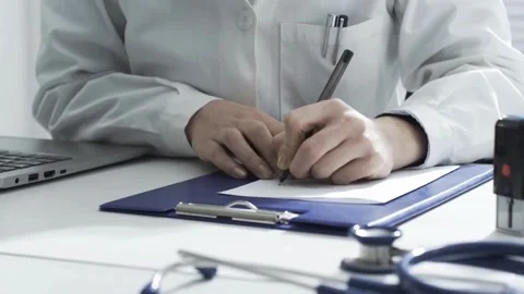 Close-up writing Young physician with stethoscope prescribes treatment to Stock Footage 336587717