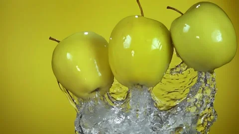 Close-up of yellow apple bouncing from water with splashes of green background Stock Footage 288527216