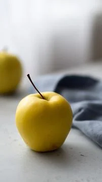 Close-Up of Yellow Apple by Window with Another Apple in the Background Stockfoto's