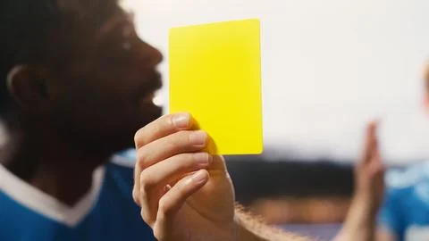 Close-up of yellow card held by referee hand after rules violation during match Stock Photos