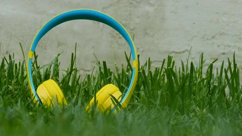 Close-up of yellow colored wireless noise cancelling headphones in the grass Stock Footage 130535264