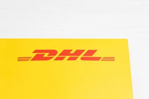 Close-up yellow DHL envelope with red logo on white wooden table. Stock Photos