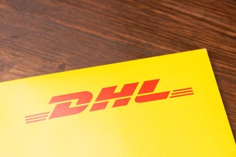 Close-up yellow DHL envelope with red logo on wooden table. Stock Photos