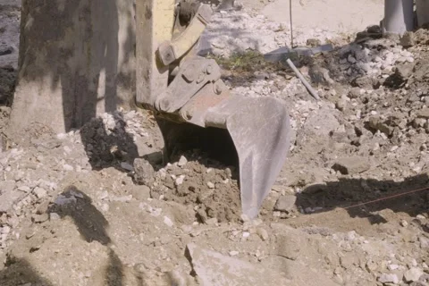 Close up of yellow excavator bucket digging dirt and rubble at construction site Vidéo 345412381