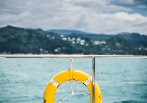 Close-up Yellow life ring hanging on boat with ocean background. 스톡 사진