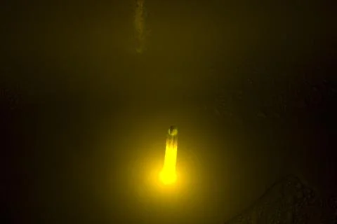 Close-up of a yellow light bulb in a dark room. Stock Photos