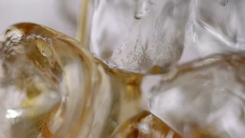 Close-up of a yellow liquid draining between ice cubes. Stock Footage 77630534