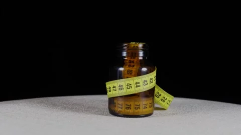 Close-up yellow measuring tape inside medicine bottle rotates on the turntable Video stock 277972531
