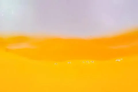 Close-up of a yellow-orange liquid surface with bubbles Stock Photos