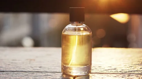 Close-up yellow perfume bottle spray on tire surface with lens flare sun rays Stock Footage 130454051