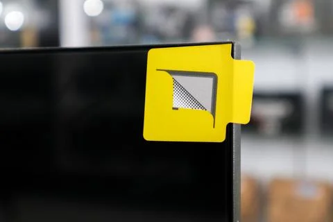 Close up of a yellow pull tab sticker on the corner of a black monitor scre.. Stock Photos
