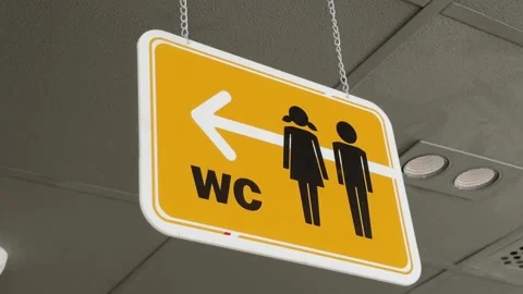 Close up of yellow Restroom Directional Sign hanging on the ceiling Inside Fast Stock Footage 343696231