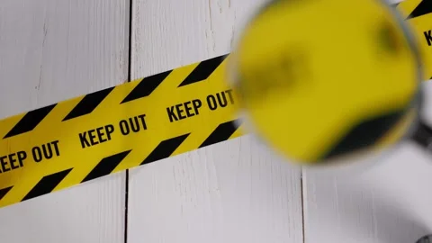 A close-up of a yellow ribbon with a warning KEEP OUT through a magnifying glass Stock Footage 329276253
