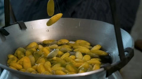 Close up of yellow silk cocoons being unraveled into fine silk threads from hot Stock Footage 315851065