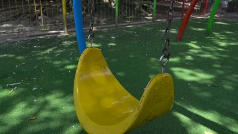 A close up of a yellow swing swaying at playground Stock Footage 230239555